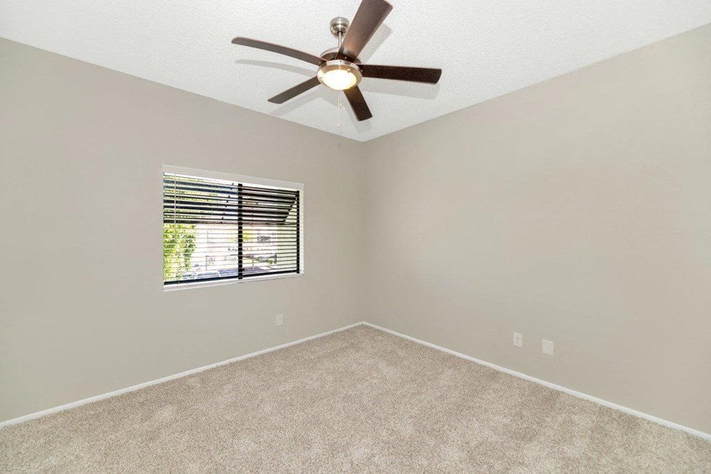 a bedroom with a ceiling fan and a window