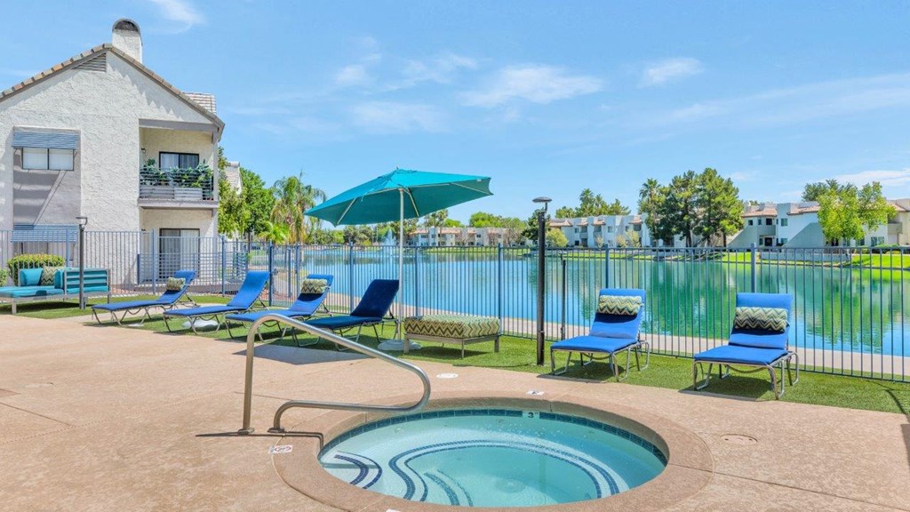 a pool with lounge chairs and an umbrella next to a building