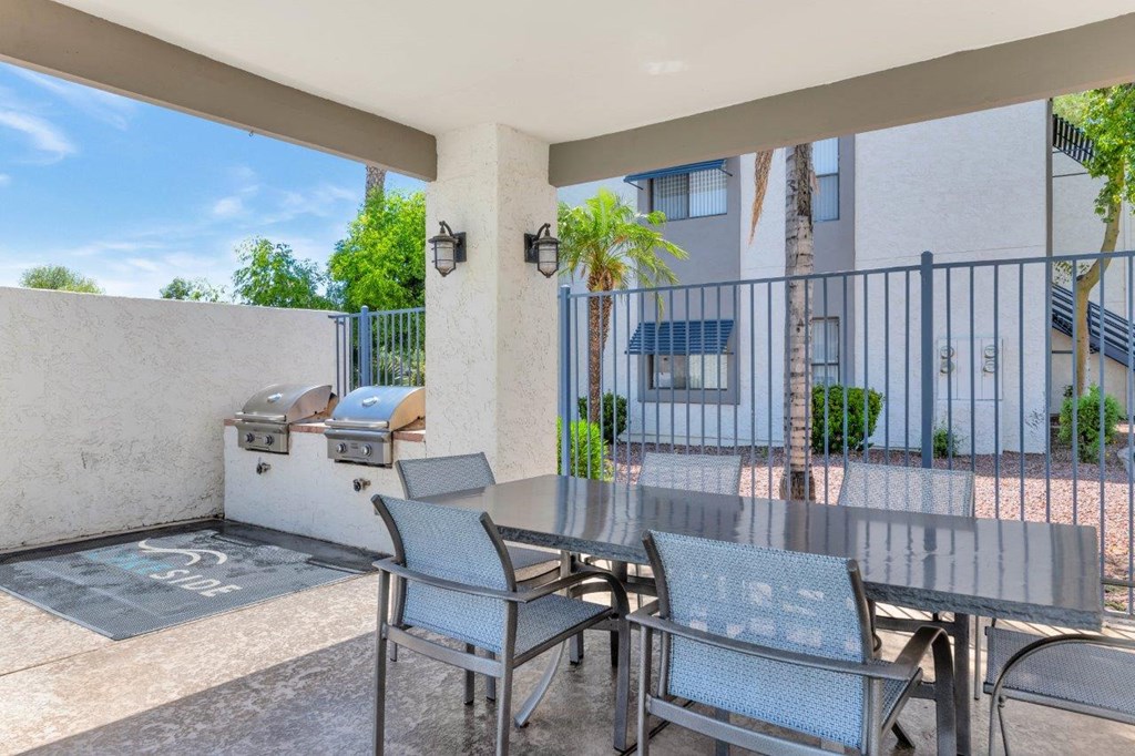 a patio with a table and chairs and a grill