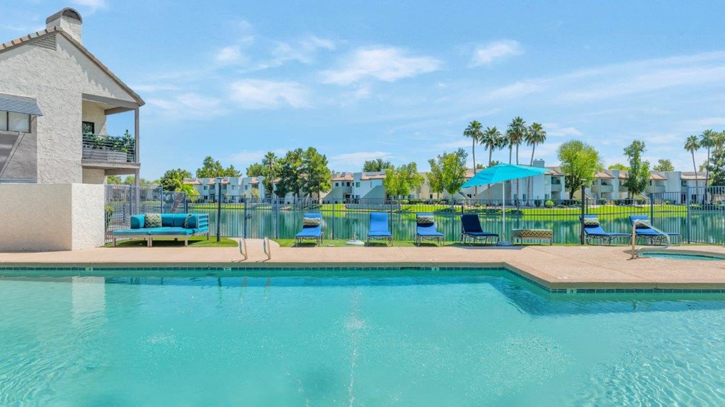 a swimming pool with a house and palm trees in the background