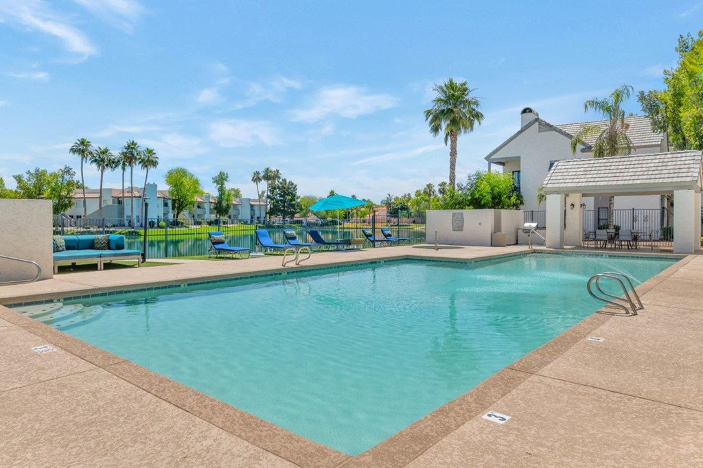 a swimming pool with a house and palm trees in the background
