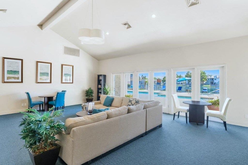 a living room with a couch table and chairs and a pool in the background
