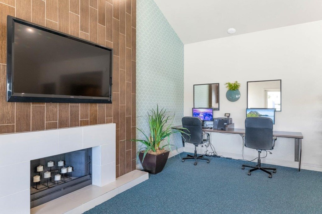 a room with a fireplace and two desks with computers
