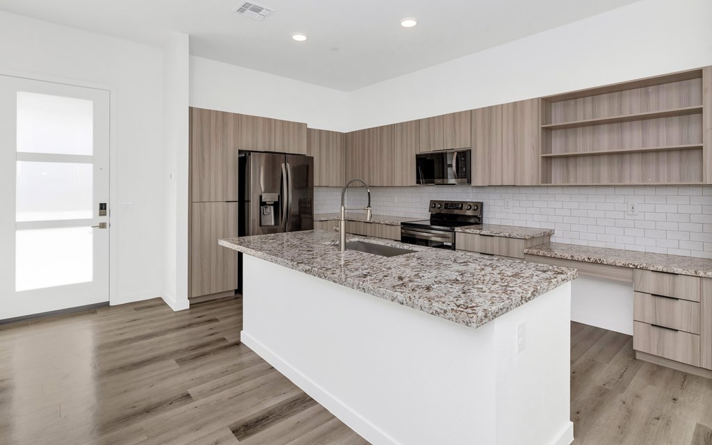 A kitchen with a granite countertop and wooden flooring at Marketside Villas at Verrado, Buckeye, AZ