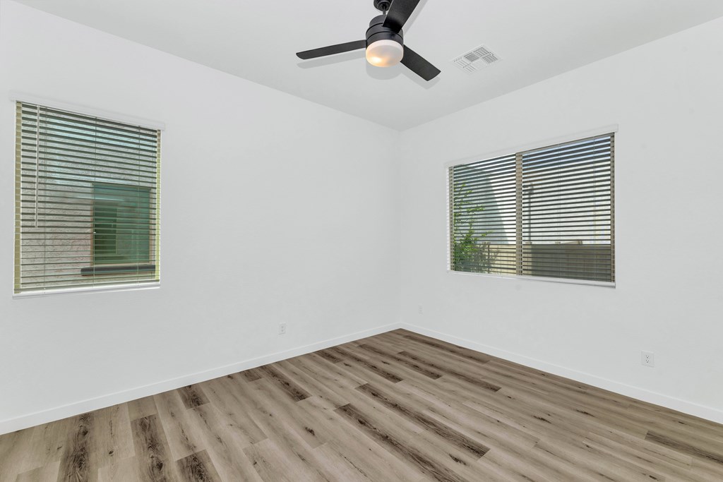 A room with a ceiling fan and two windows with blinds at Marketside Villas at Verrado, Buckeye, AZ