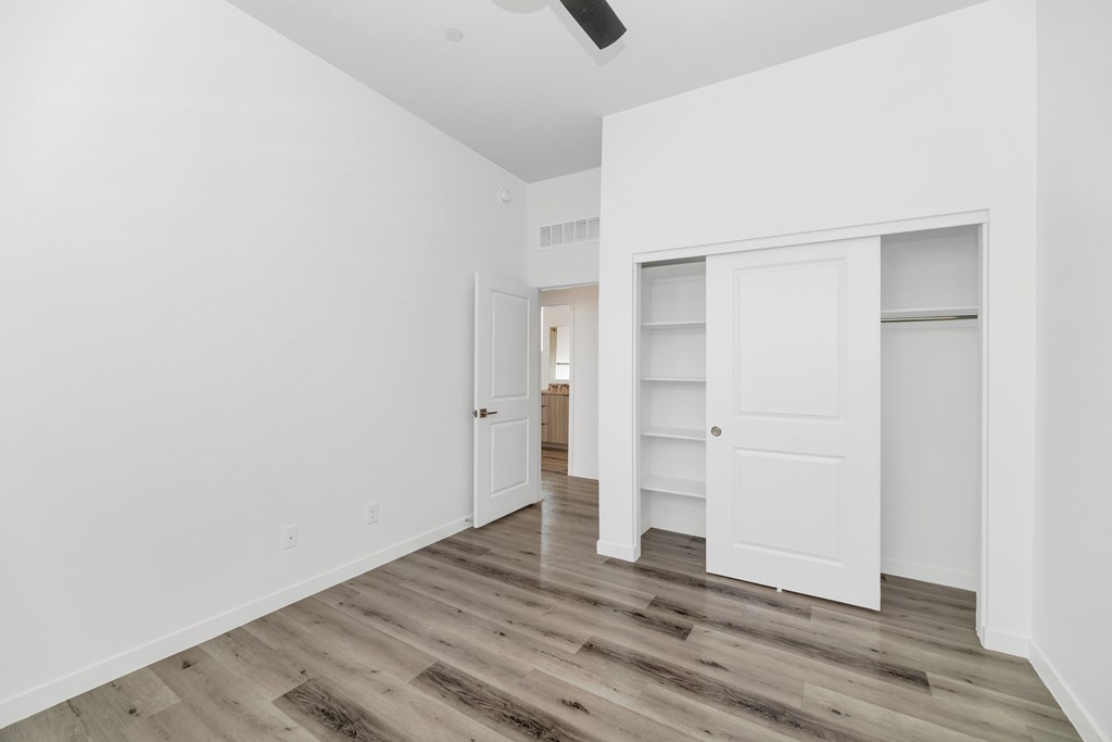 A room with white walls and wooden flooring with a door on the left and a closet on the right at Marketside Villas at Verrado, Buckeye, AZ