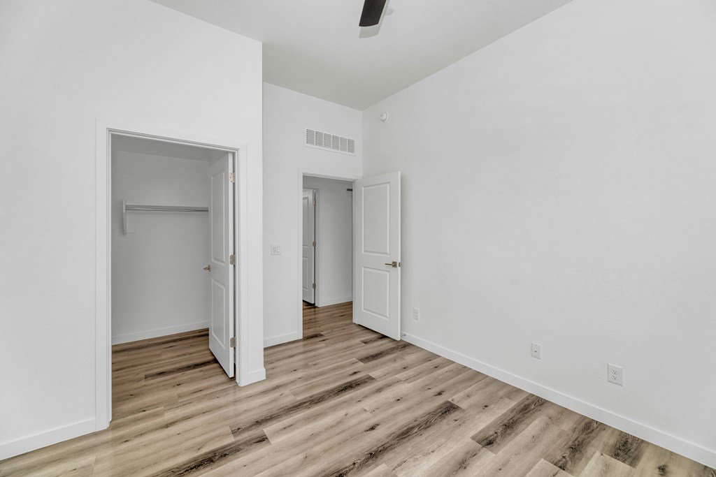 A room with white walls and wood flooring with two open doors at Marketside Villas at Verrado, Buckeye, AZ