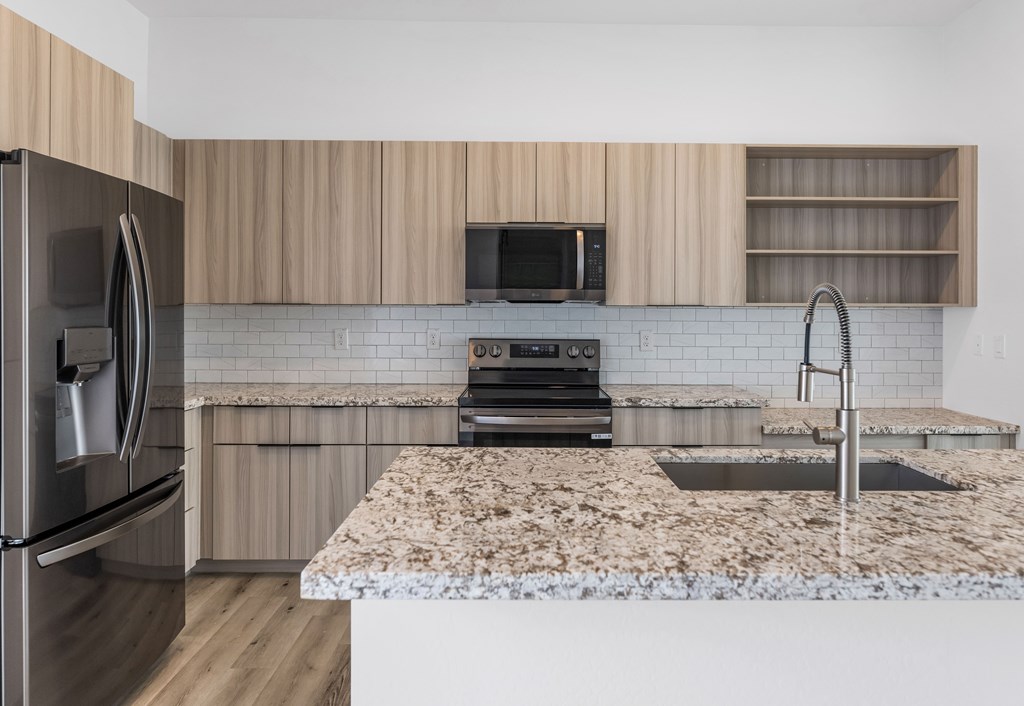 A kitchen with a granite countertop and stainless steel appliances at Marketside Villas at Verrado, Buckeye, AZ