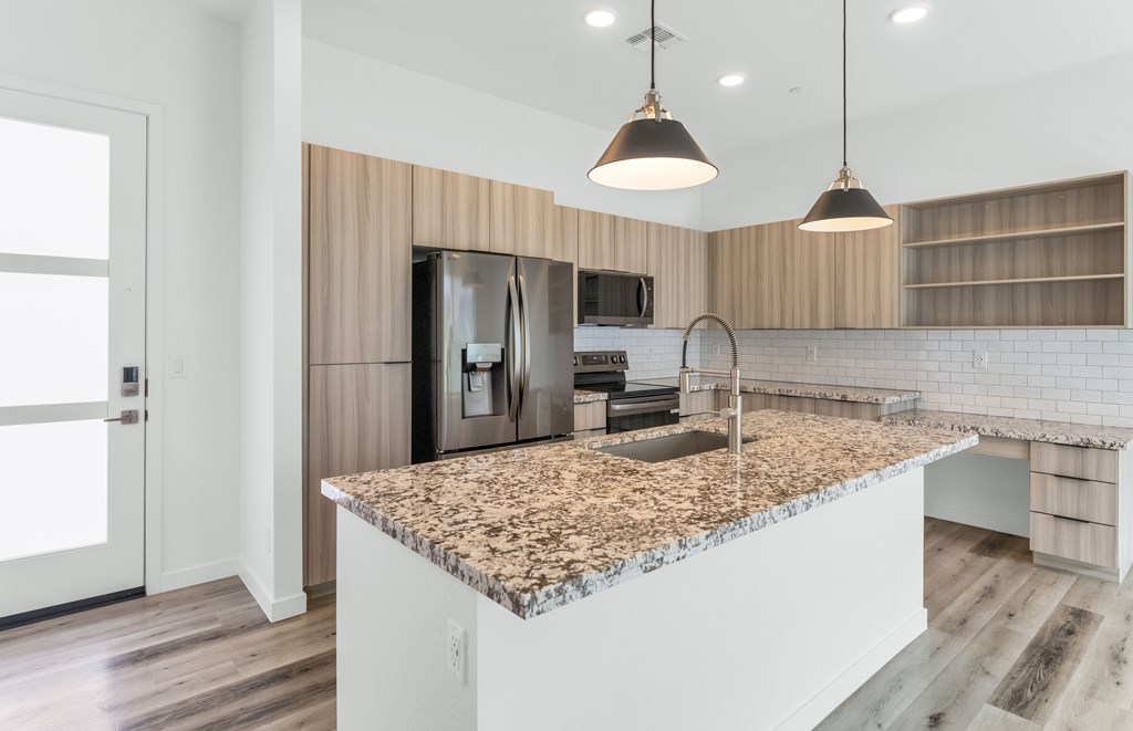 A kitchen with a granite countertop and a sink at Marketside Villas at Verrado, Buckeye, AZ