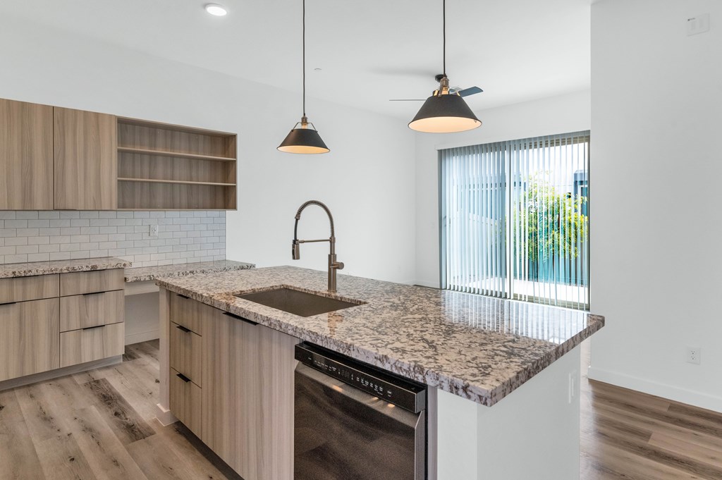 A modern kitchen with a granite countertop and wooden cabinets at Marketside Villas at Verrado, Buckeye, AZ