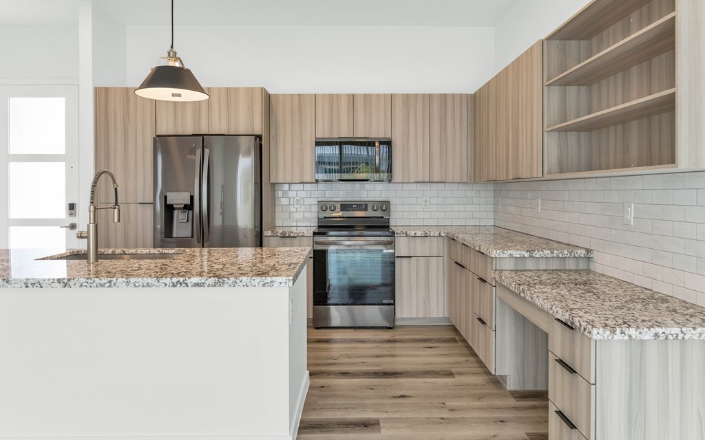 A modern kitchen with wooden cabinets and a marble countertop at Marketside Villas at Verrado, Buckeye, AZ