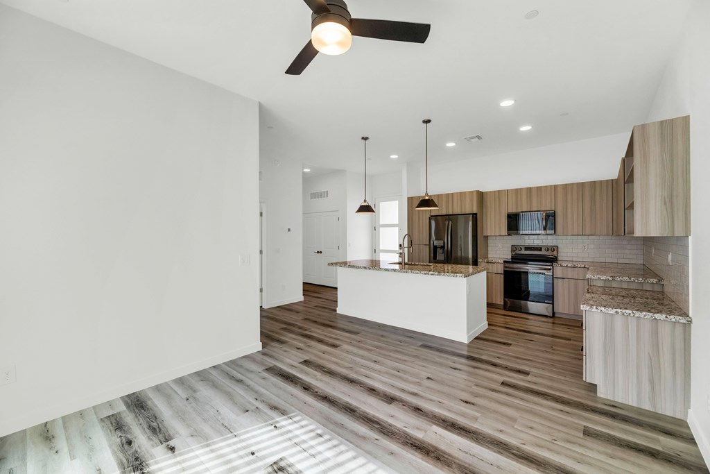 A modern kitchen with wooden floors and a ceiling fan at Marketside Villas at Verrado, Buckeye, AZ