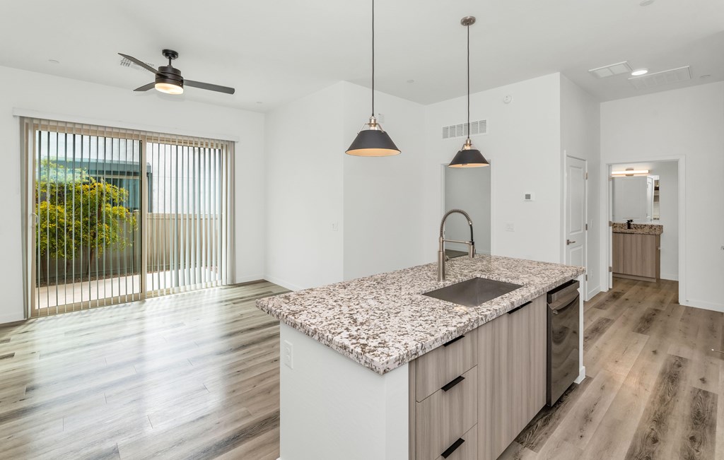 A modern kitchen with a marble countertop and wooden flooring at Marketside Villas at Verrado, Buckeye, AZ