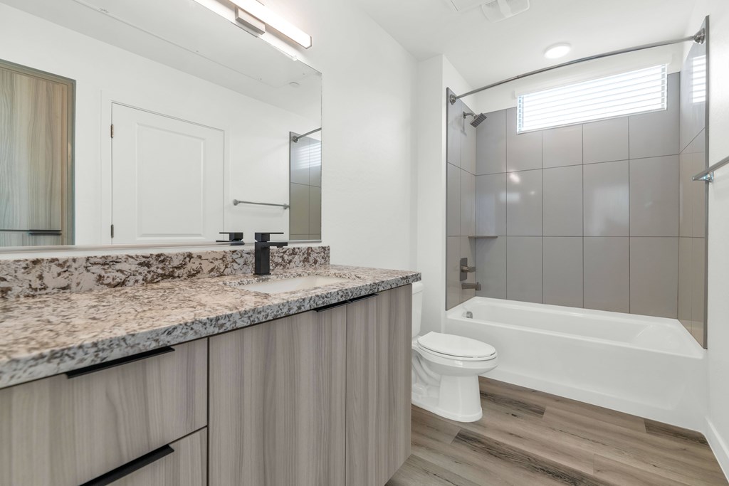 A modern bathroom with a marble countertop and a white toilet at Marketside Villas at Verrado, Buckeye, AZ