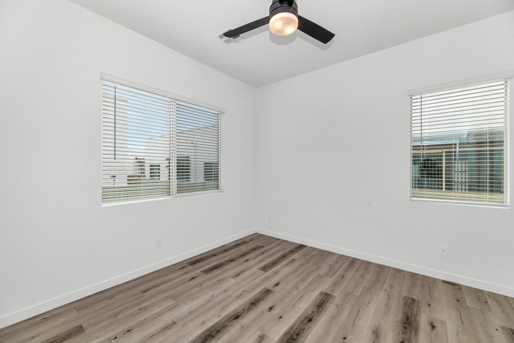 A room with a ceiling fan and wooden flooring at Marketside Villas at Verrado, Buckeye, AZ