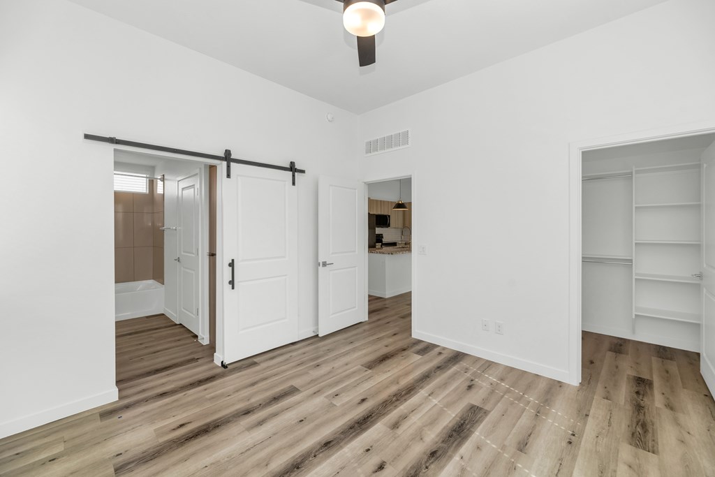A room with white walls and wooden flooring, featuring a sliding door and a bar shelf at Marketside Villas at Verrado, Buckeye, AZ