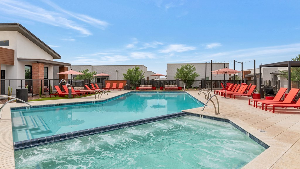 A large swimming pool with red lounge chairs around it at Marketside Villas at Verrado, Buckeye, AZ
