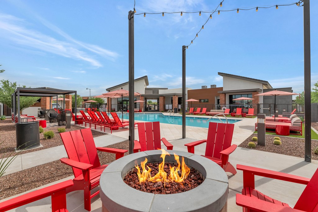 A living room with a grey couch, a blue chair, a fireplace and a red carpet at Marketside Villas at Verrado, Buckeye, AZ
