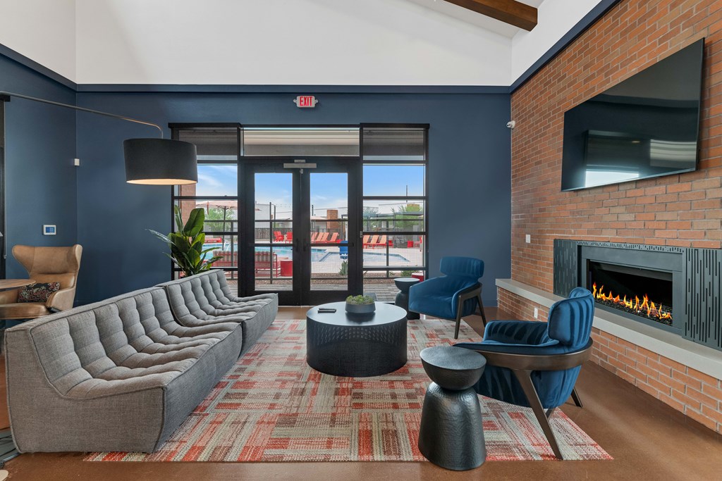 A living room with a grey couch, a blue chair, a fireplace and a red carpet at Marketside Villas at Verrado, Buckeye, AZ