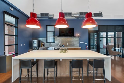 A kitchen with a table and chairs and three red pendant lights.