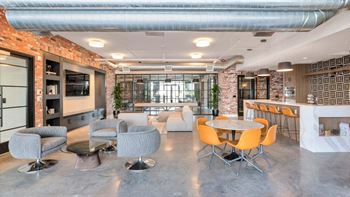 a room with a table and chairs and a brick wall in the background at The Common Apartments, Phoenix,85018