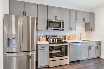 a kitchen with gray cabinets and stainless steel appliances at The Common Apartments, Arizona 85018