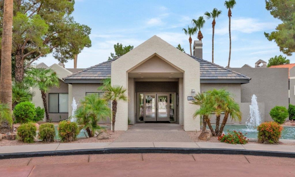 a house with a fountain and palm trees in front of it