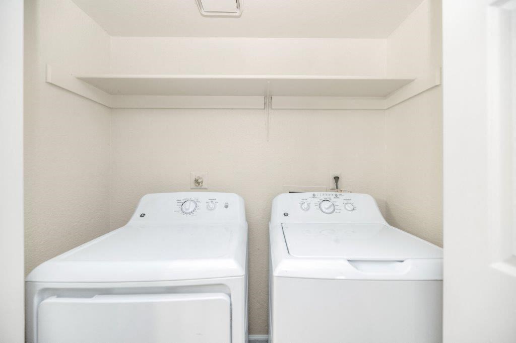 two white washers and dryers in an empty laundry room