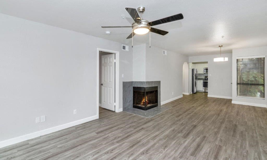 an empty living room with a fireplace and a ceiling fan