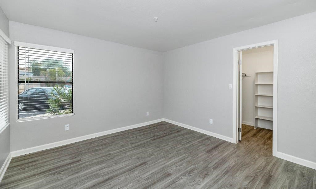 an empty living room with a large window and wooden floors