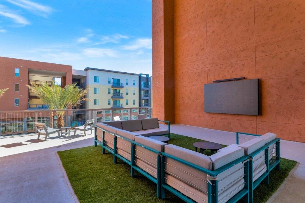 a patio with a couch and a television on the side of a building