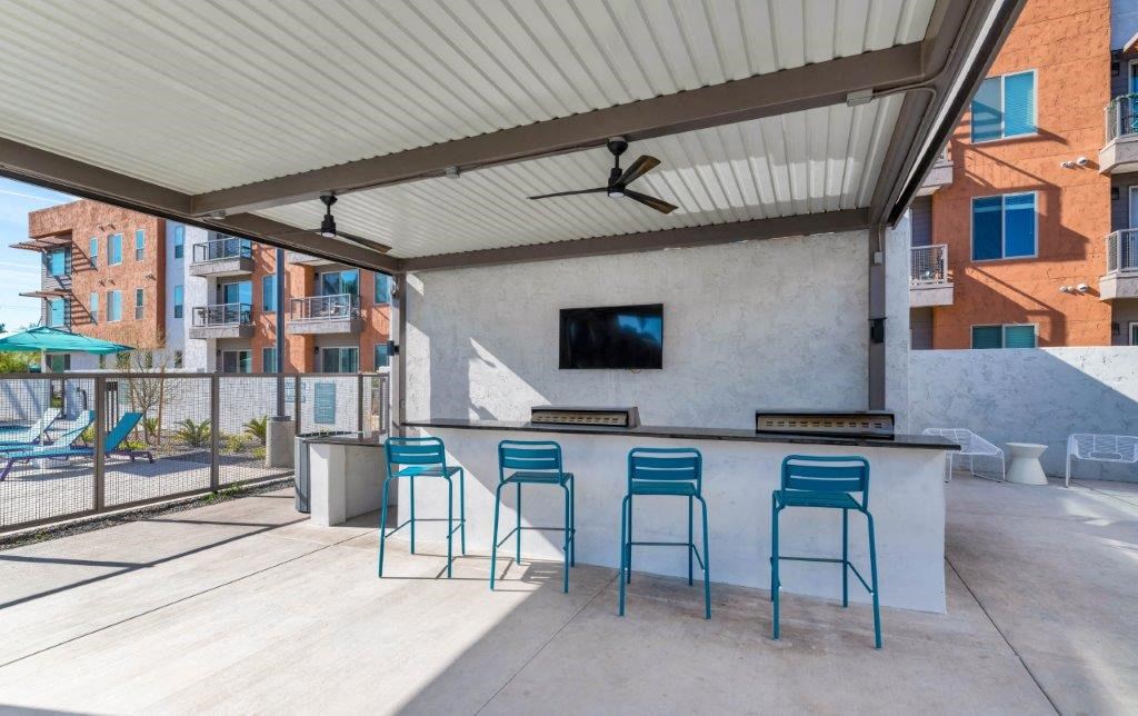 a bar with blue stools in a patio with a tv