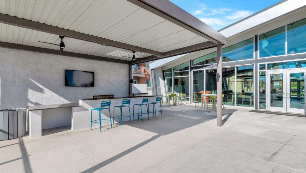 a patio with a bar and chairs and glass doors