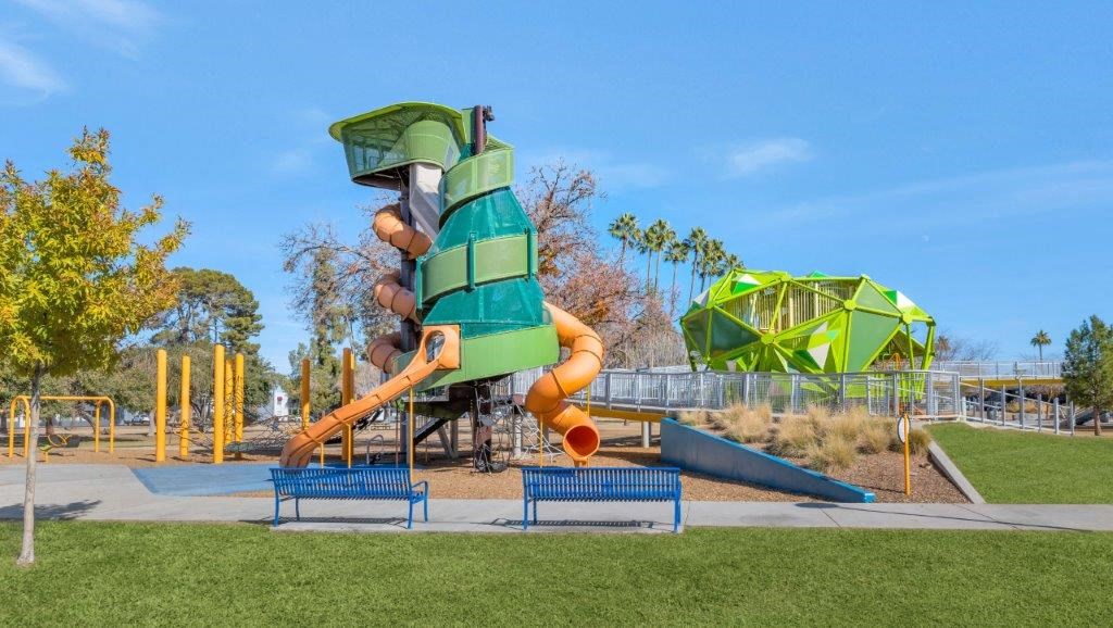 a childrens playground with a large green and orange slide