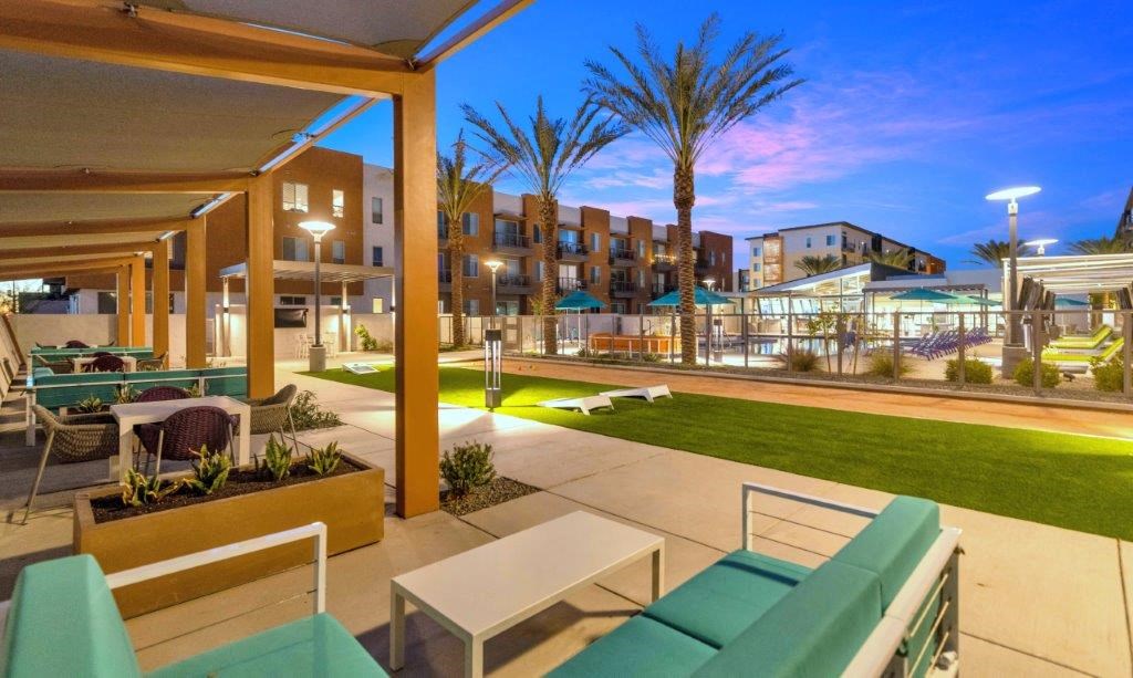 a large patio with furniture and a lawn at night