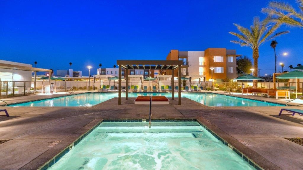 a swimming pool at night with a building in the background