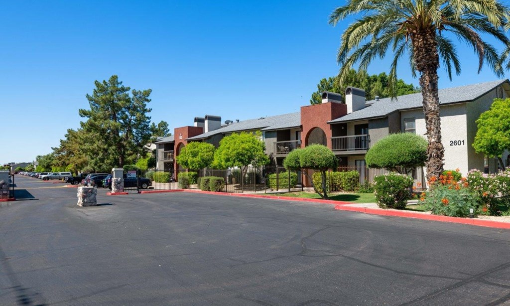 an empty street in front of an apartment building with palm trees