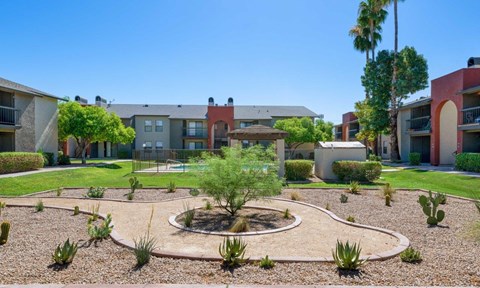 A courtyard with a circular garden in the middle surrounded by apartment buildings at Reflections at Red Mountain Apartments, Mesa