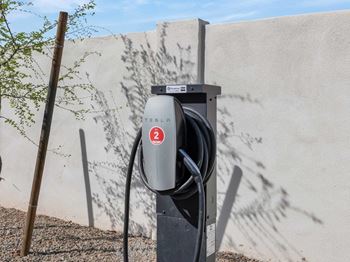 a black electric car charger in front of a white wall with a red sticker on it  at Glen 91, Arizona, 85305