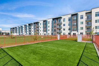 a grassy area with a fenced in area in front of an apartment building  at Glen 91, Glendale, AZ, 85305