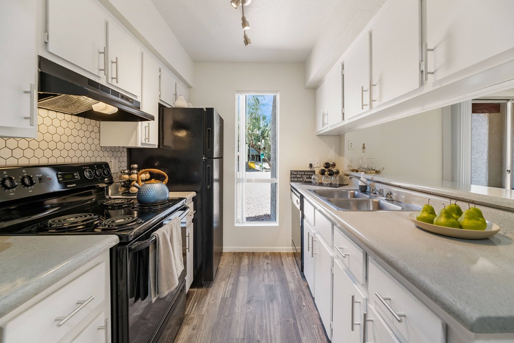 a kitchen with white cabinets and black appliances and a window  at Glen Brae, Glendale