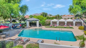 a resort style pool with lounge chairs and umbrellas