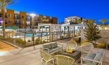 a patio with chairs and a fire pit at night
