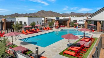 a swimming pool with red chairs and umbrellas at a resort at Marketside Villas at Verrado, Buckeye, 85396