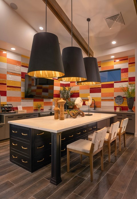 the kitchen has a large island with chairs and two large hanging lights