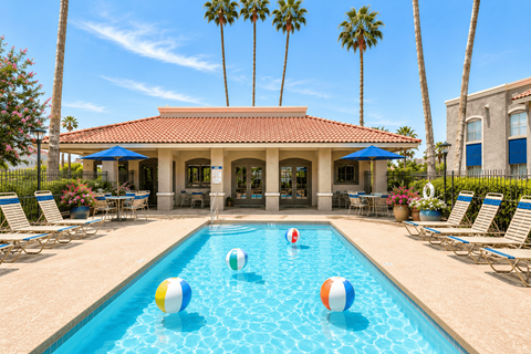 A pool with a house and palm trees in the background.