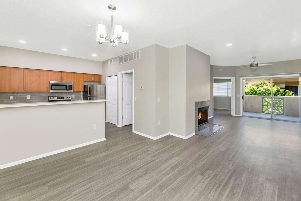 an empty living room with a fireplace and a kitchen