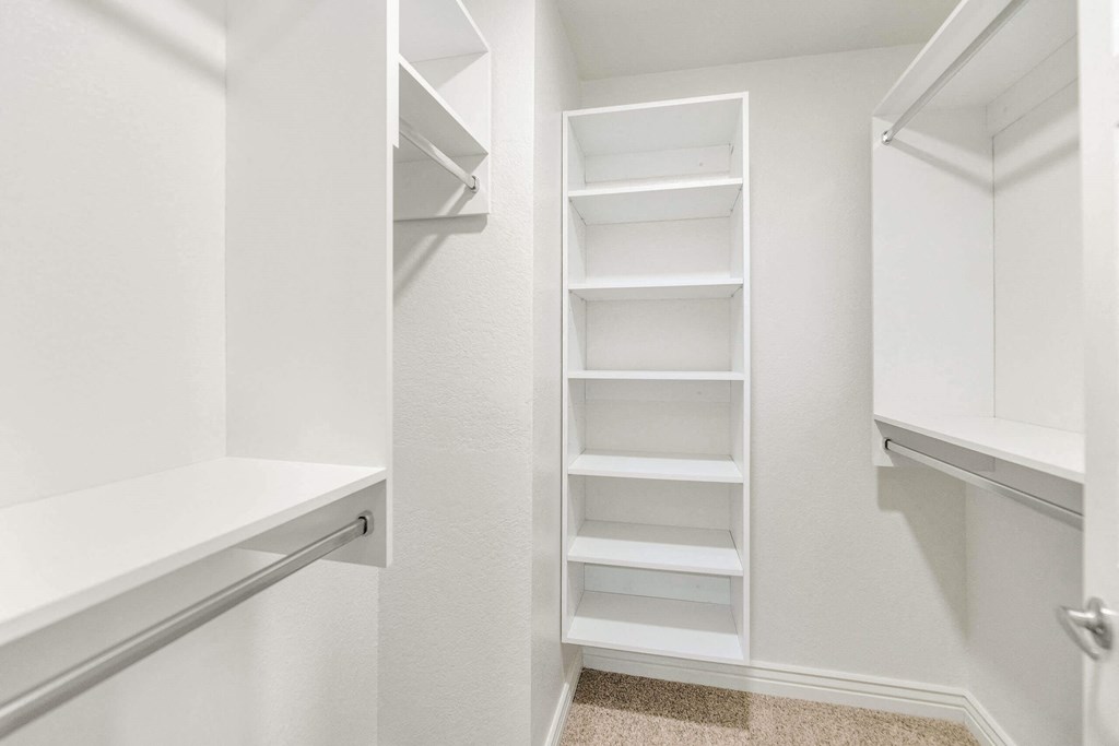 a closet in a white room with shelves and