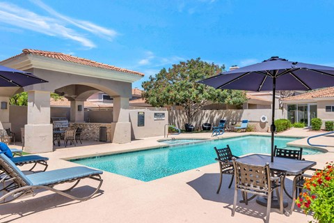 a swimming pool with patio furniture and umbrellas