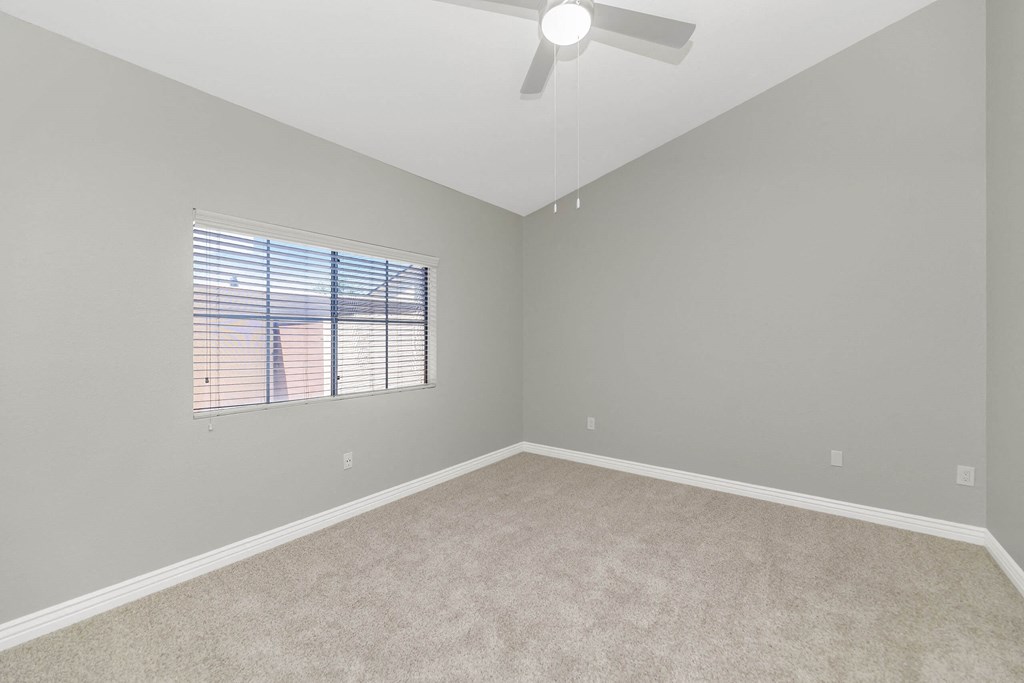 an empty room with a window and a ceiling fan